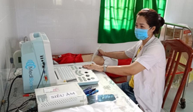 Cán bộ y tế thực hiện siêu âm cho bệnh nhân đến khám tại Trạm Y tế xã Tân Hòa.